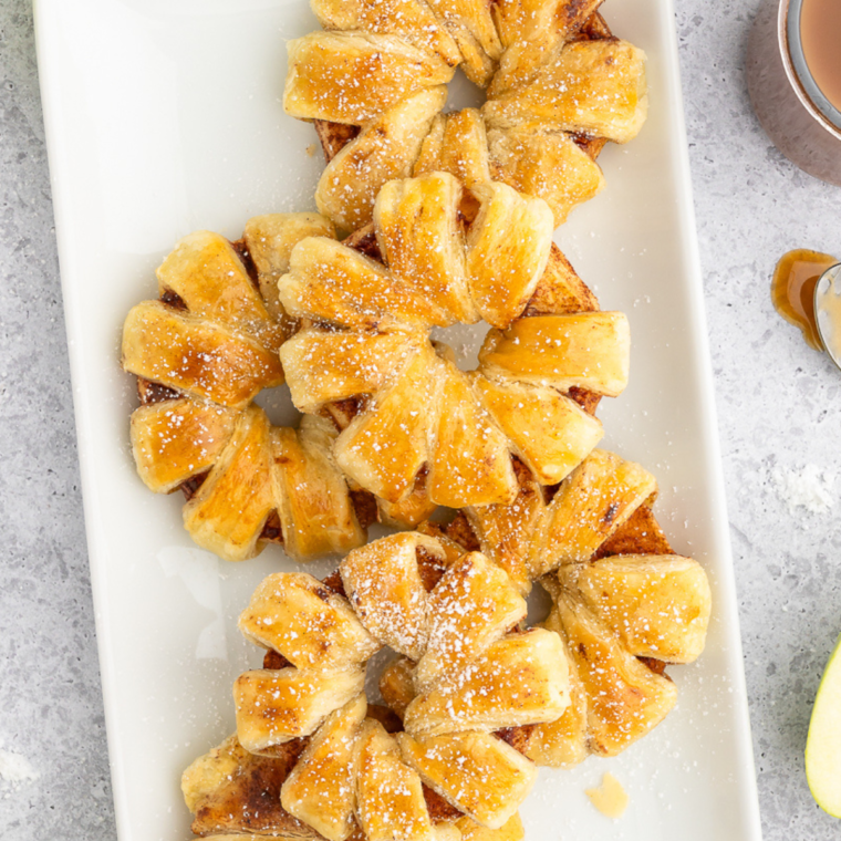 Air Fryer Puff Pastry Apple Rings served on a white plate, featuring a golden-brown finish and a light dusting of powdered sugar.