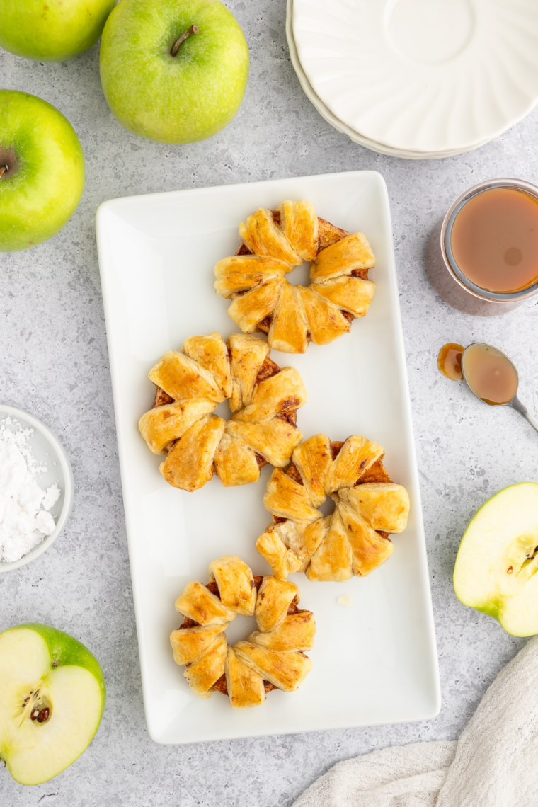 Plate of Air Fryer Puff Pastry Apple Rings, beautifully arranged and garnished with a dusting of powdered sugar, showcasing their golden-brown flaky texture.