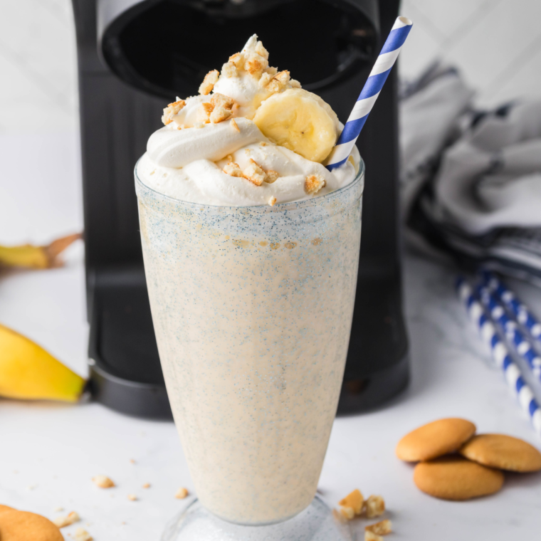 A refreshing Sonic Banana Shake made with ripe bananas, vanilla ice cream, and topped with whipped cream and banana slices, served in a tall glass with a colorful straw.