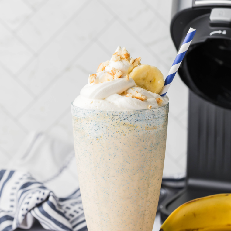 A refreshing Sonic Banana Shake made with ripe bananas, vanilla ice cream, and topped with whipped cream and banana slices, served in a tall glass with a colorful straw.