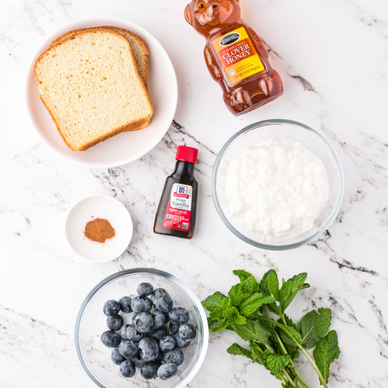 Ingredients for air fryer blueberry cottage cheese toast laid out on a marble surface.