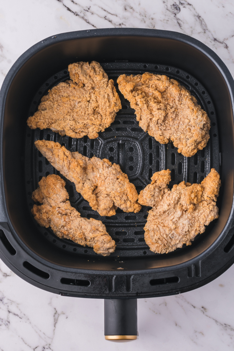 Frozen chicken tenders in the air fryer basket before cooking