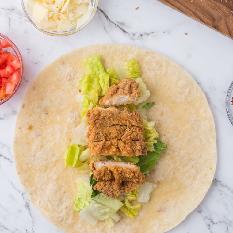 Rolling up a chicken Caesar wrap on a kitchen counter