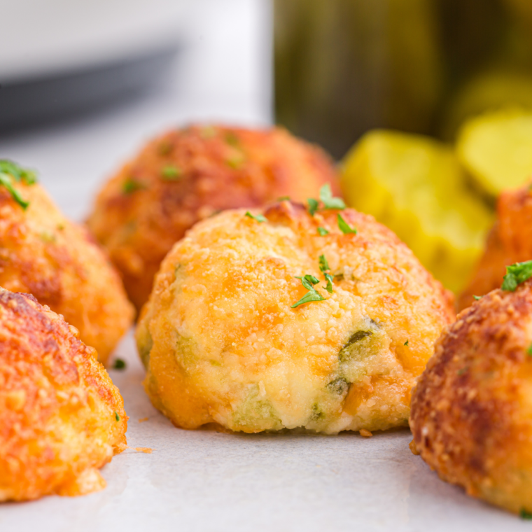 Golden brown air fryer pickle balls served on a plate with dipping sauce.