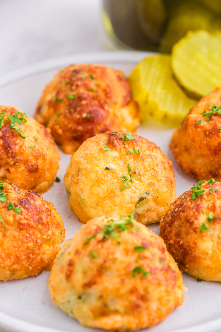 Hand holding a crispy air fryer pickle ball dipped in sauce.
