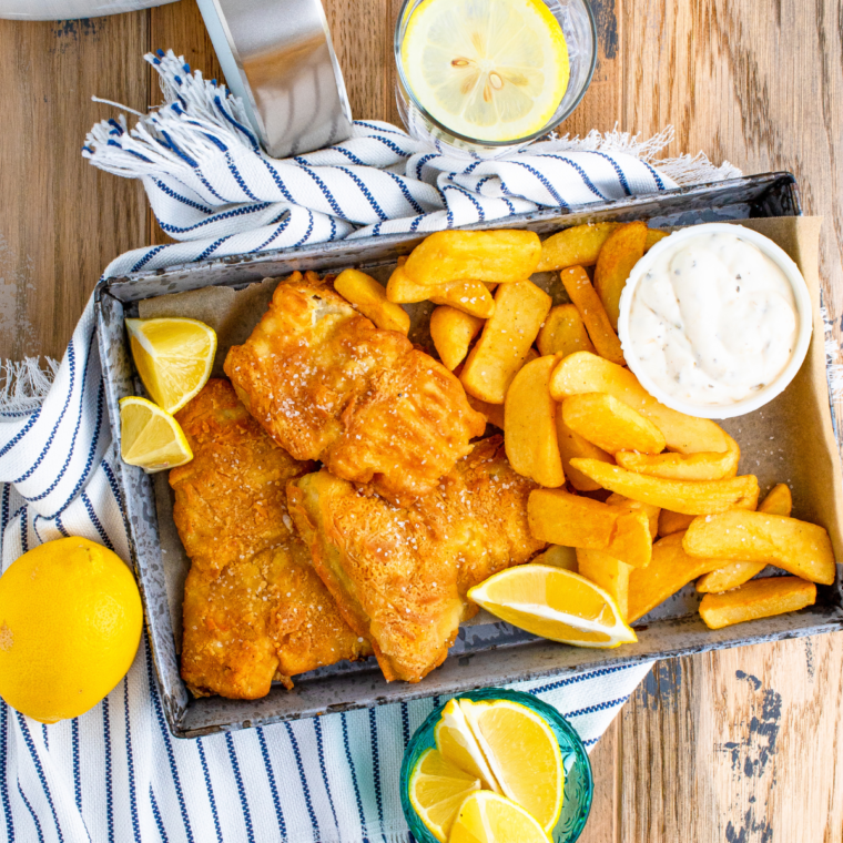 Drain and Serve: Crispy fried fish fillets draining on a paper towel-lined plate, served with tartar sauce and sides.