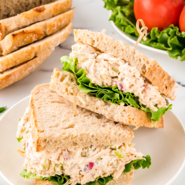: A serving of Copycat Chicken Salad Chick Classic Carol on a bed of greens with crackers on the side.