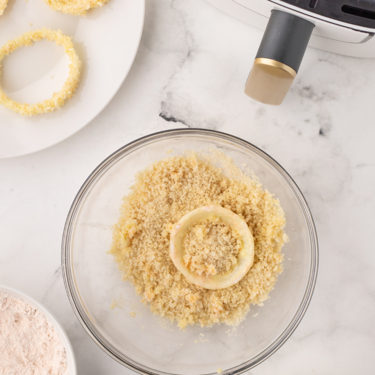 "Dip each onion ring into the batter, ensuring it’s fully coated, then roll it in breadcrumbs for a crispy coating."