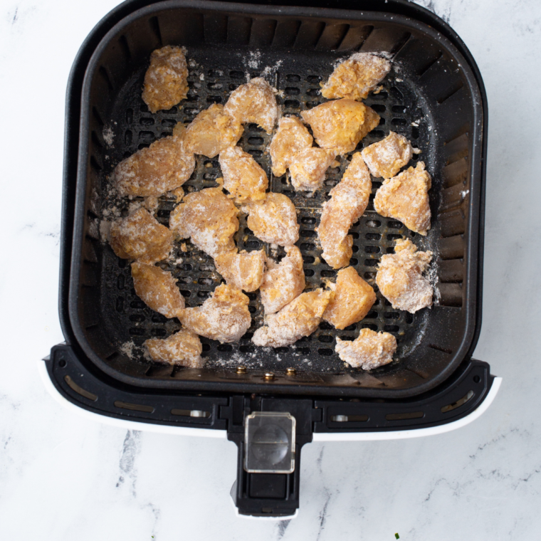 Breaded chicken bites arranged in a single layer in the air fryer basket