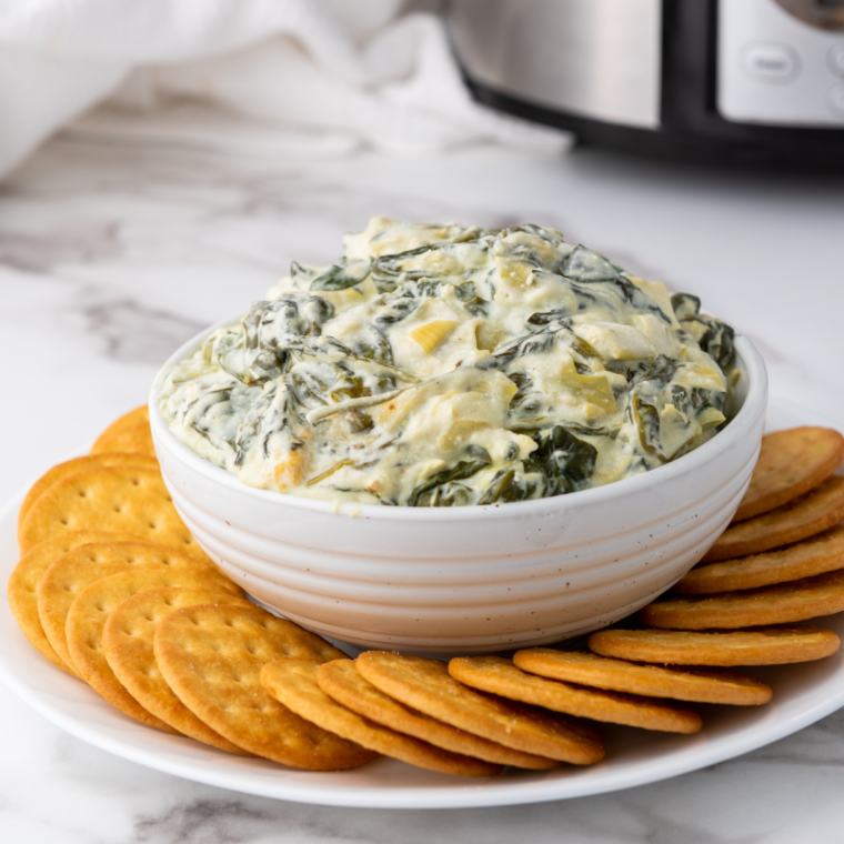 Plate of creamy Ninja Foodi Possible Cooker Pro spinach artichoke dip served warm with a rich, cheesy texture and visible spinach and artichoke pieces.