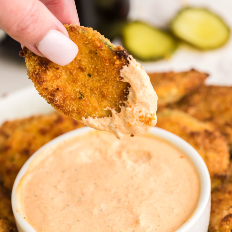 Close-up of crispy air fryer pickle nickels, a copycat of Red Robin’s, served with a side of dipping sauce.