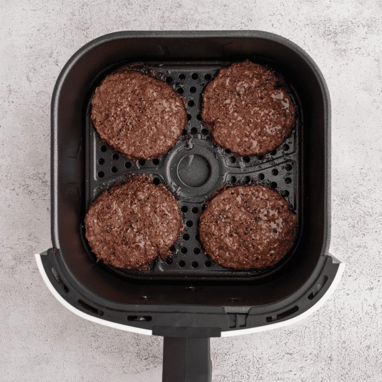 Air frying burger patties in the air fryer basket for 8-10 minutes, flipping halfway through.