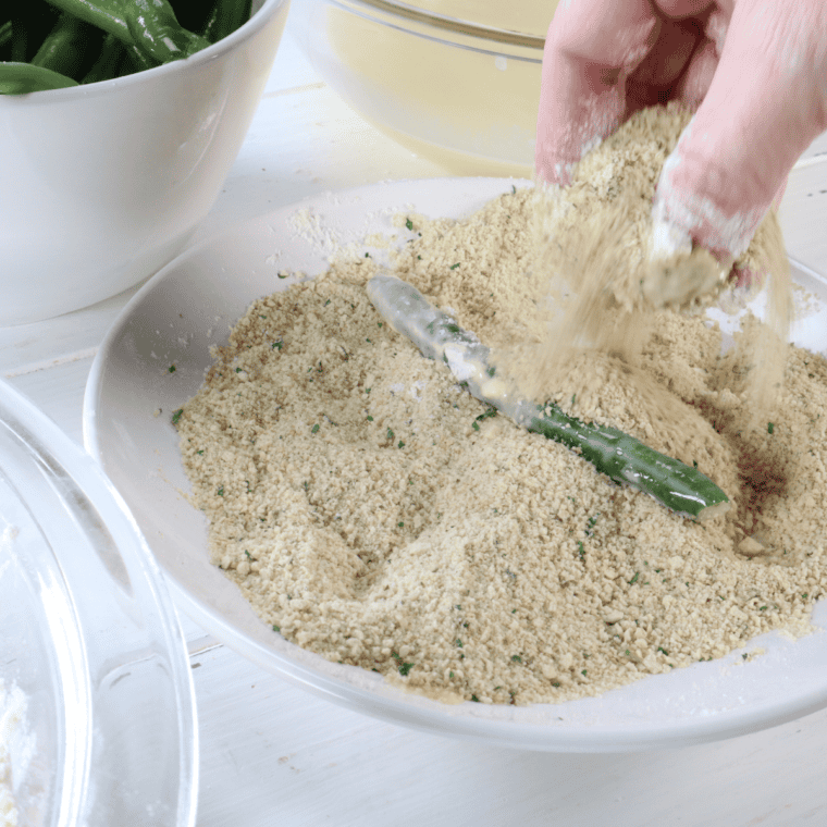Coating green beans by dipping in flour, egg, and breadcrumb mixtures