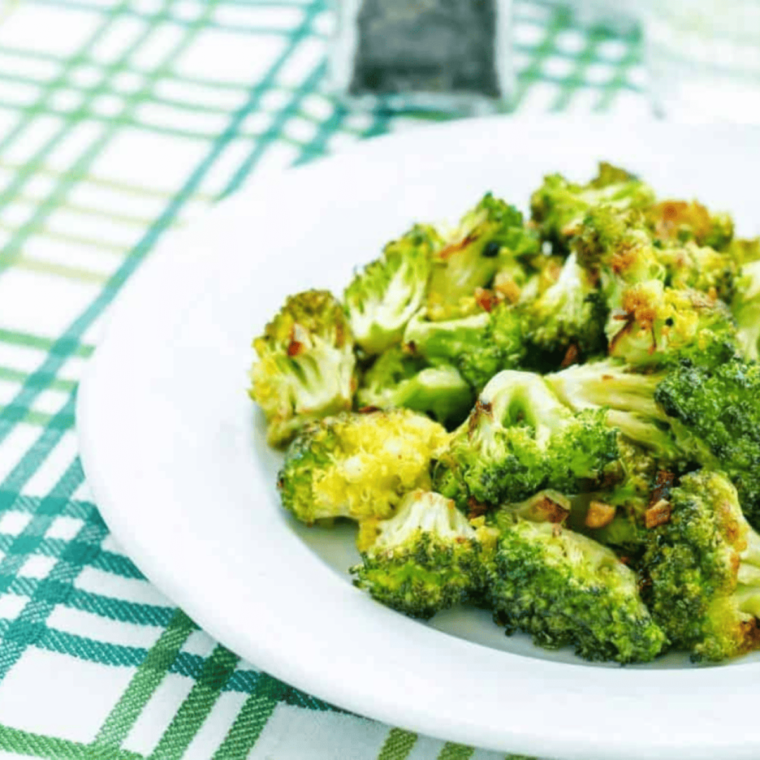 Close-up of bright green broccoli florets glossy with garlic butter and seasoning.