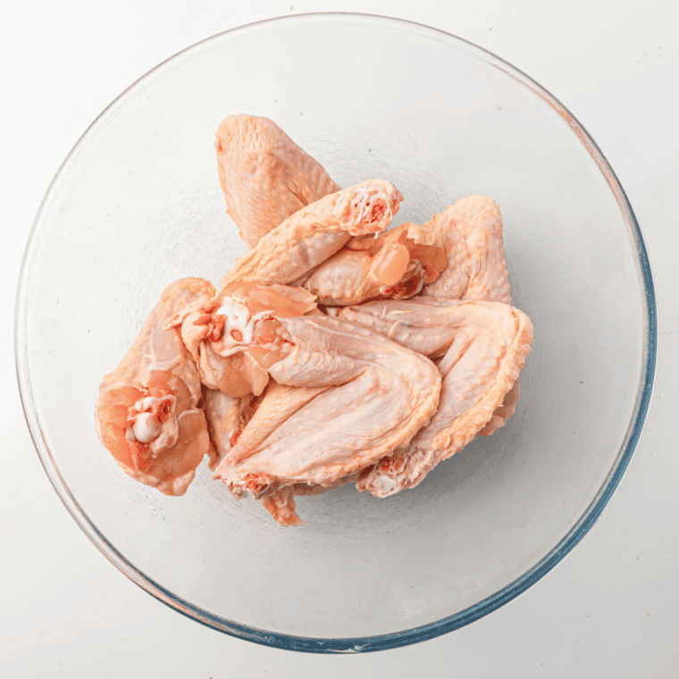 Air fryer preheating to 400°F with chicken wings seasoned with olive oil, garlic powder, and salt ready for cooking.