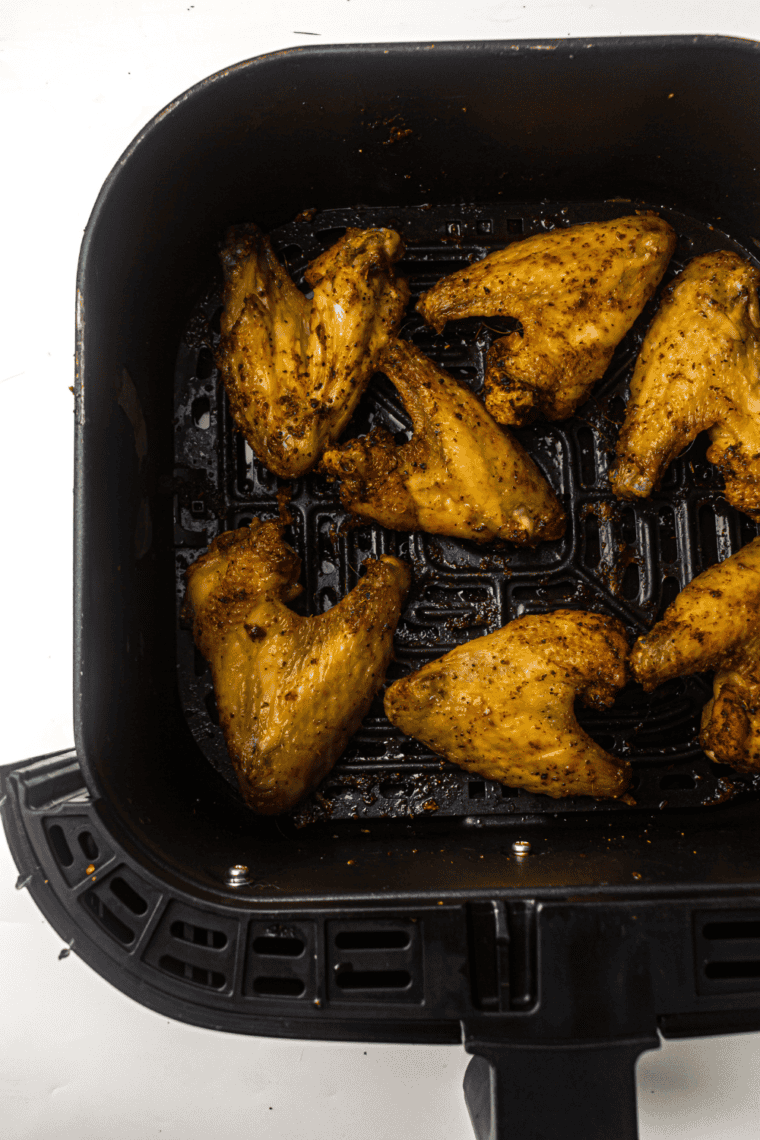 Plate of crispy Wingstop Lemon Pepper Wings garnished with lemon slices and sprinkled with fresh herbs.