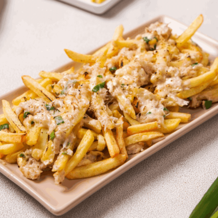 Plate of crispy fries topped with melted cheese, crab meat, and green onions, inspired by Red Lobster’s Crabby Cheese Fries.