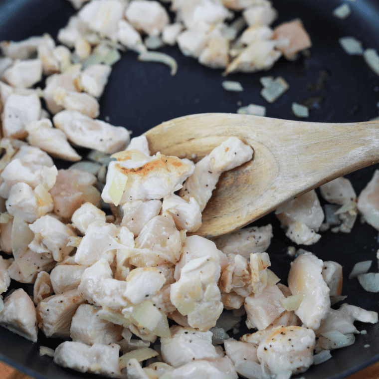 Seasoned diced chicken cooking with garlic in a skillet