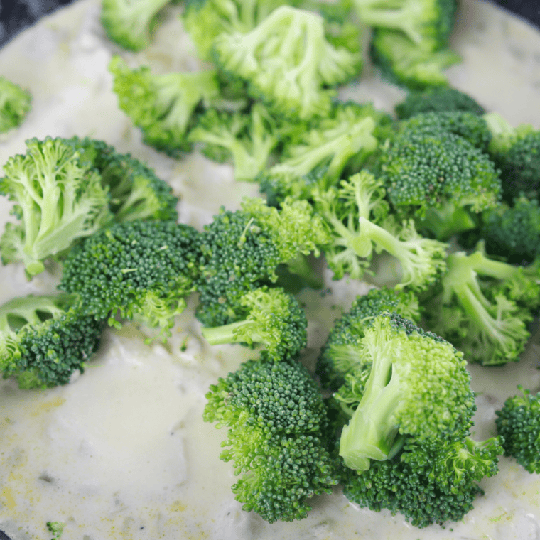 White rice simmering in cream and chicken broth in a skillet