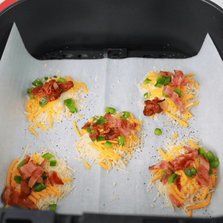 Assembled cheese crisp seasoned with salt and pepper, ready to go into the air fryer basket.
