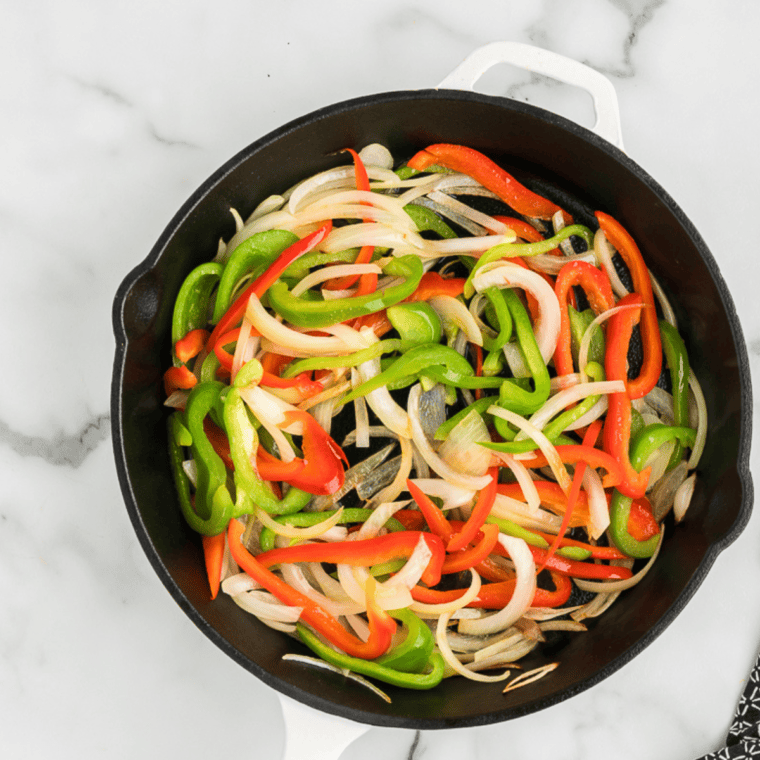 Slicing bell peppers and onions, heating olive oil, and sautéing onions until softened.