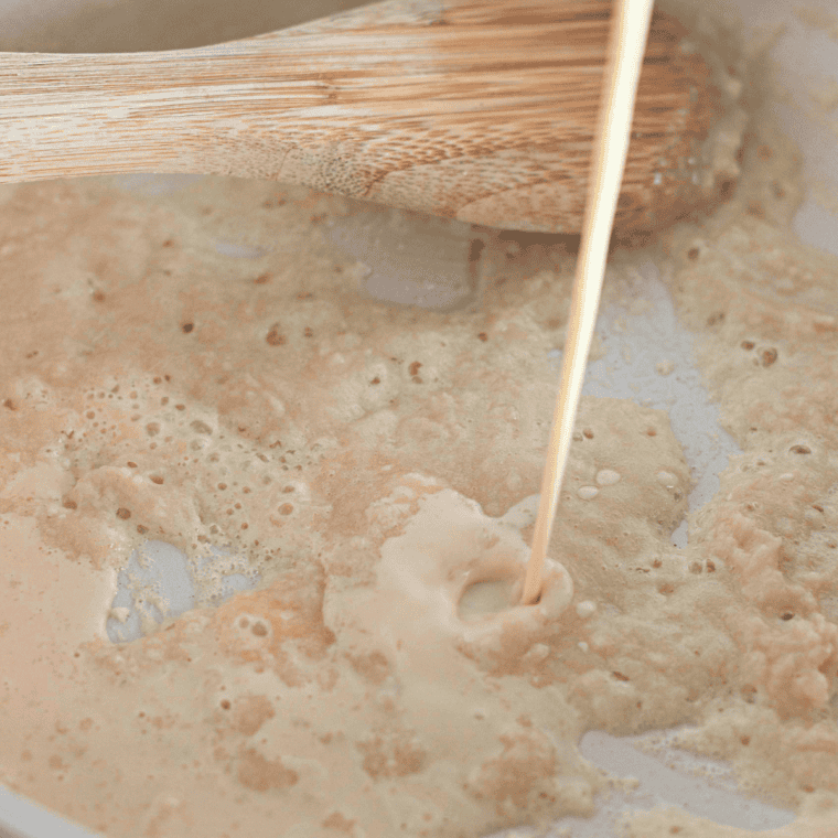 Melted butter and flour being whisked together in a saucepan to create a smooth, golden roux for mac and cheese.