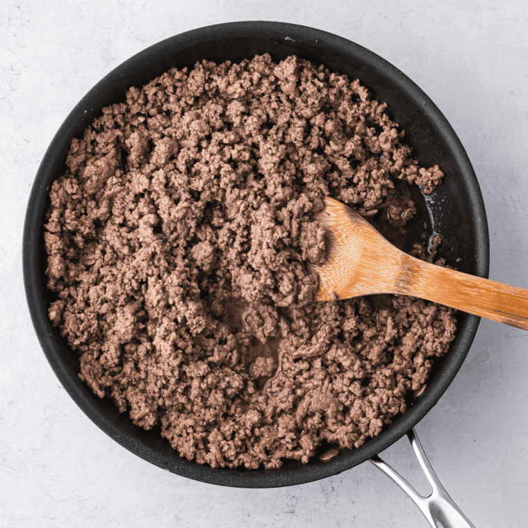 Ground beef being cooked in a skillet, seasoned with salt, pepper, and Big Mac seasoning, then drained of excess fat.