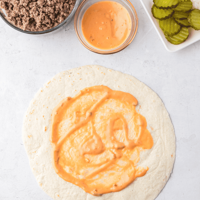 Tortillas spread with Thousand Island dressing, topped with cooked beef, cheese, lettuce, onions, and pickles.