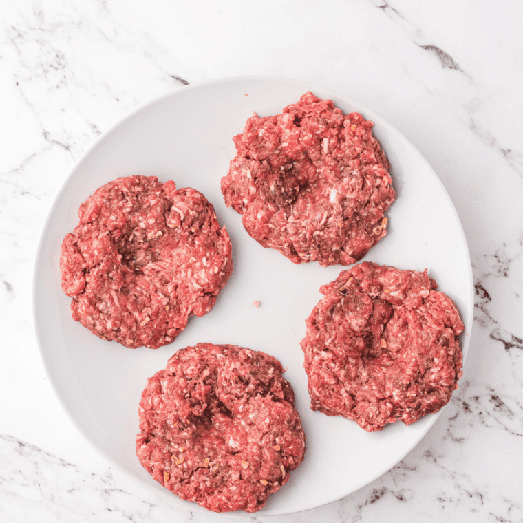Shaping burger patties from the mixture and making indentations in the center.