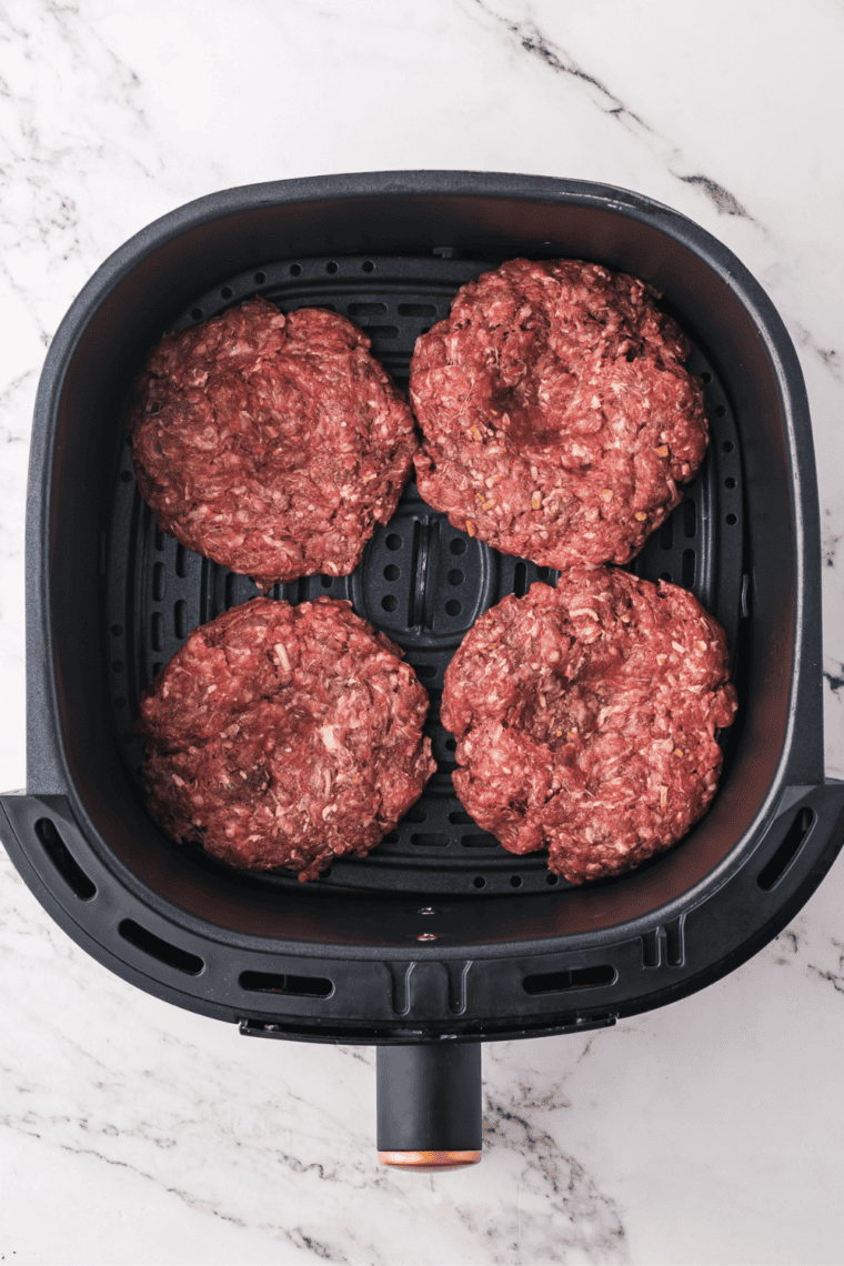 Placing burger patties in air fryer basket, cooking for 10-12 minutes, flipping halfway.