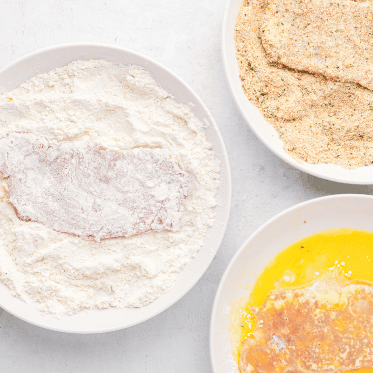 Dipping veal cutlets into flour, eggs, and breadcrumb mixture to coat for air frying.