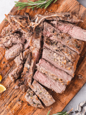 A perfectly grilled Bistecca Alla Fiorentina (Florentine steak) with a golden crust, served on a wooden board with fresh rosemary and lemon wedges.