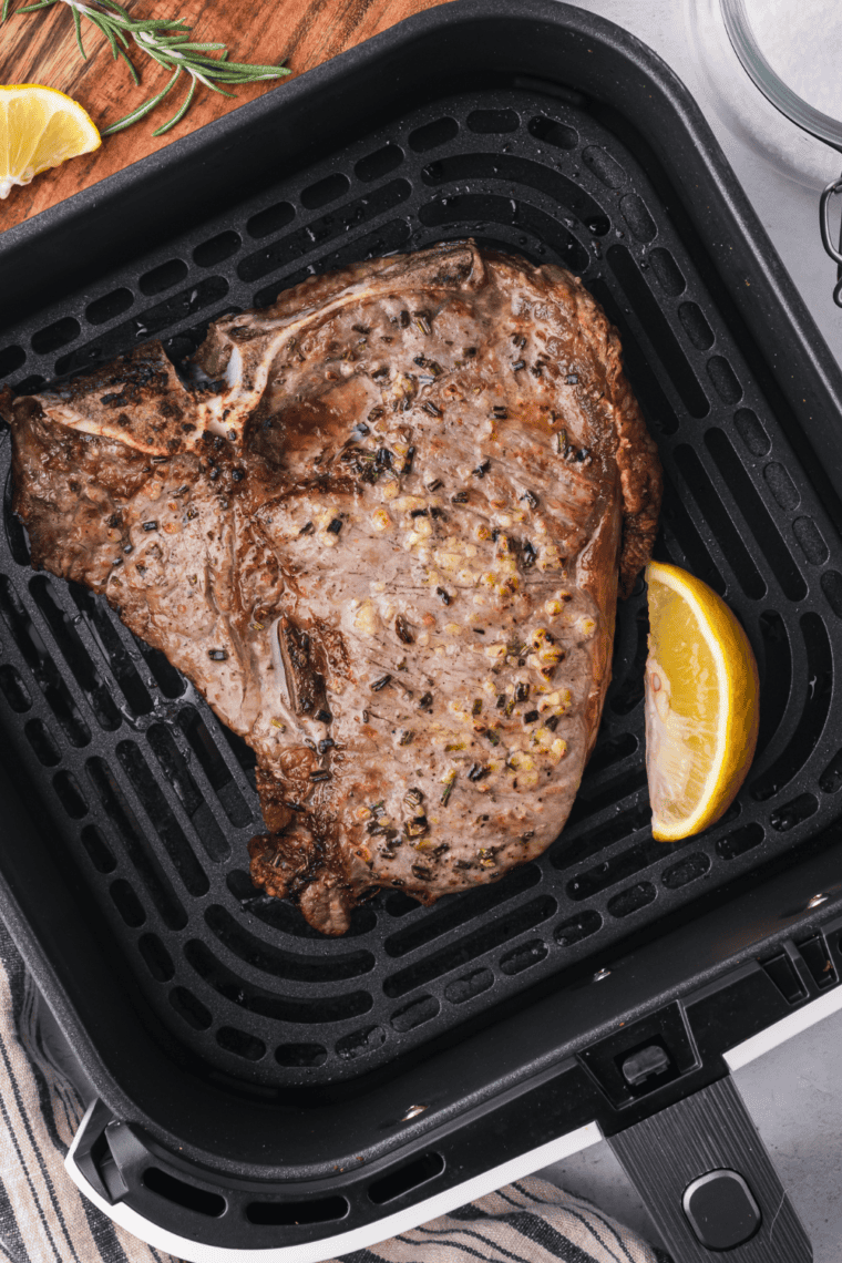 Air-fried Bistecca Alla Fiorentina (Florentine Steak) with rosemary and garlic, served with lemon wedges.