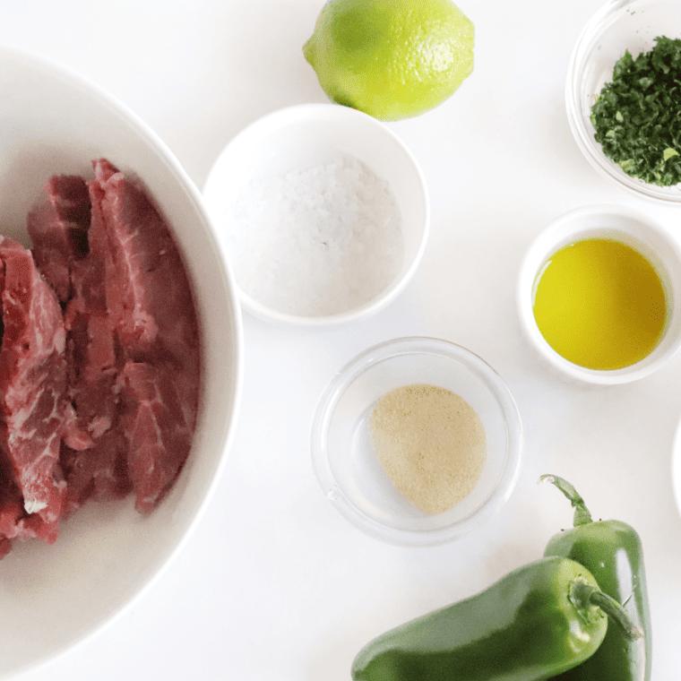 Ingredients for Copycat Chili's steak fajitas, including flank steak, lime, bell peppers, onion, and Tex-Mex spices.
