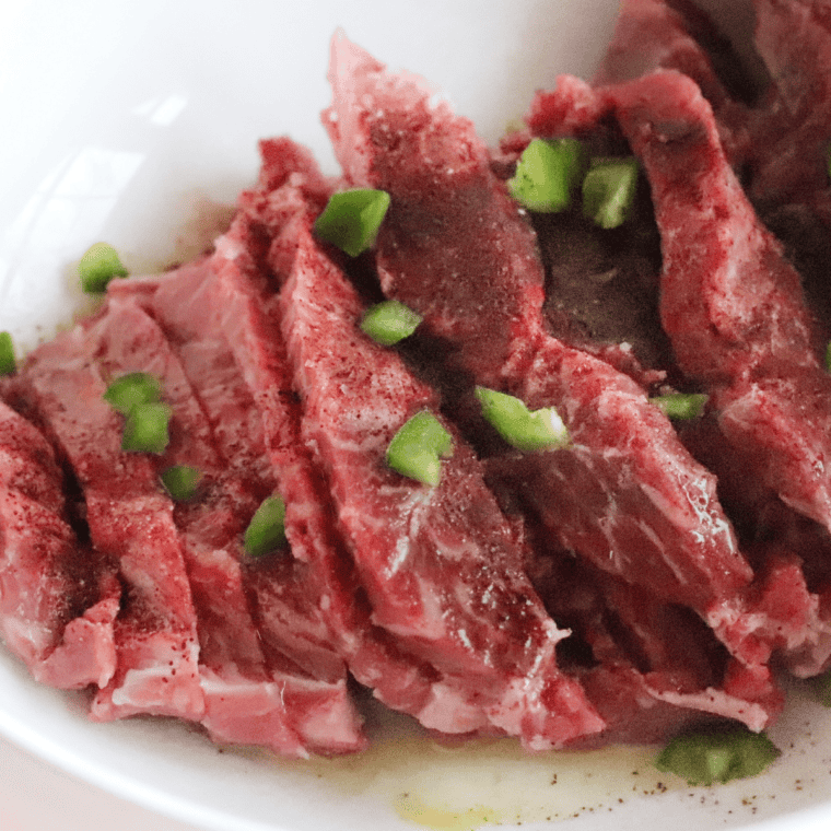 Whisking lime juice, oil, garlic, cumin, and brown sugar in a bowl to marinate flank steak for copycat fajitas.