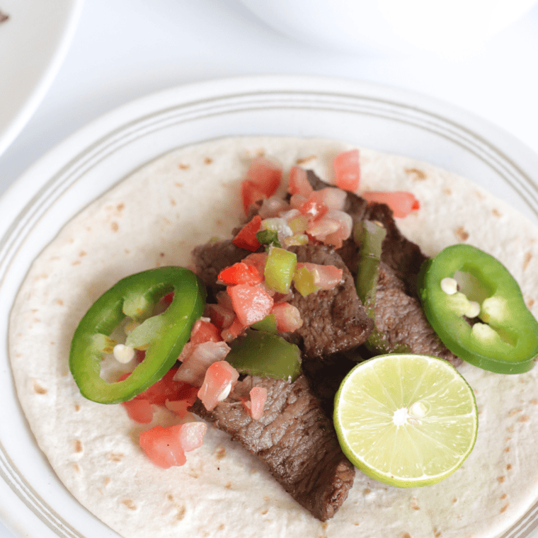 Copycat Chili's steak fajitas with sliced flank steak, peppers, onions, pico de gallo, guacamole, and sour cream.