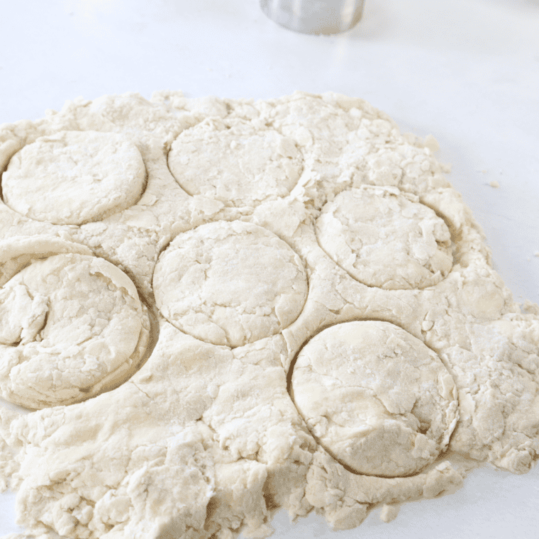 Rolling out biscuit dough to 1-inch thickness and cutting biscuits with a cutter, preheating air fryer to 350°F.