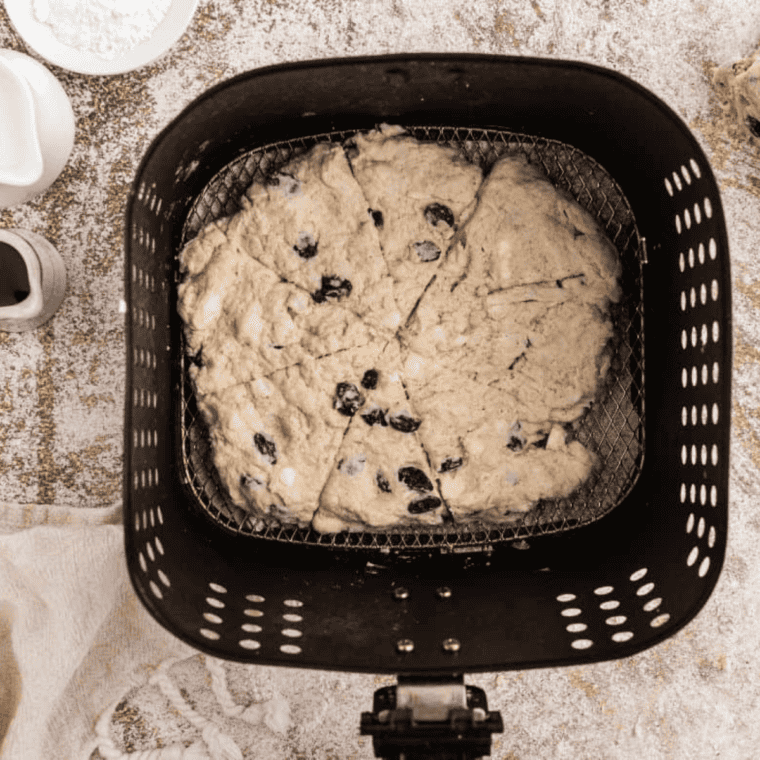 Spraying air fryer basket and placing biscuits in a single layer for cooking.