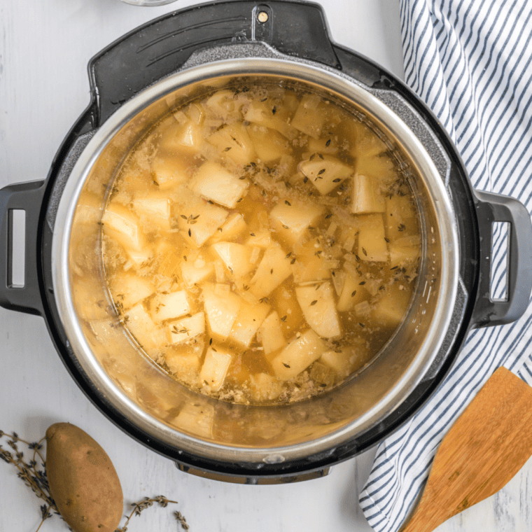 Pouring chicken broth over potatoes, ensuring they are covered.
