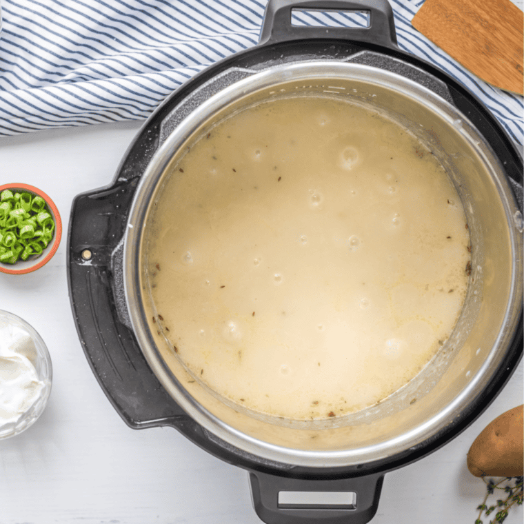 Using a potato masher to mash potatoes to desired consistency.