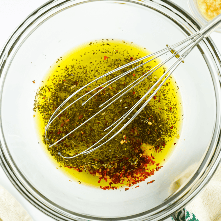 Mixing rosemary, parsley, oregano, red pepper, salt, black pepper, garlic, and Parmesan in a small bowl.