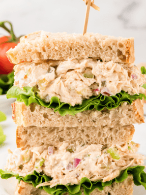 A bowl of homemade Napa Almond Chicken Salad with shredded chicken, toasted almonds, red grapes, and a creamy dressing, served with croissants.