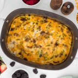 Slow cooker breakfast casserole with eggs, sausage, cheese, and hash browns served in a white dish