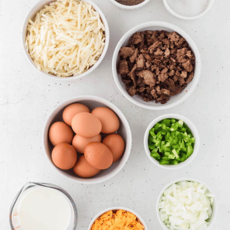Ingredients for slow cooker breakfast casserole: eggs, sausage, hash browns, cheese, peppers, and onion