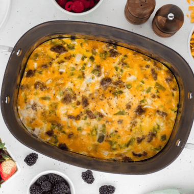 Slow cooker breakfast casserole with eggs, sausage, cheese, and hash browns served in a white dish