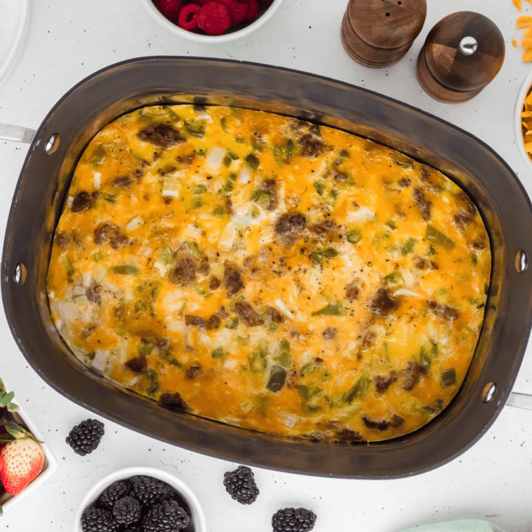 Slow cooker breakfast casserole with eggs, sausage, cheese, and hash browns served in a white dish