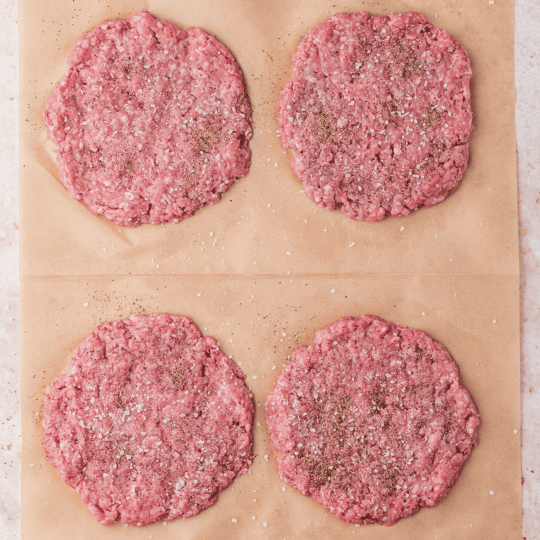 Forming ground beef into patties and seasoning with salt and pepper.