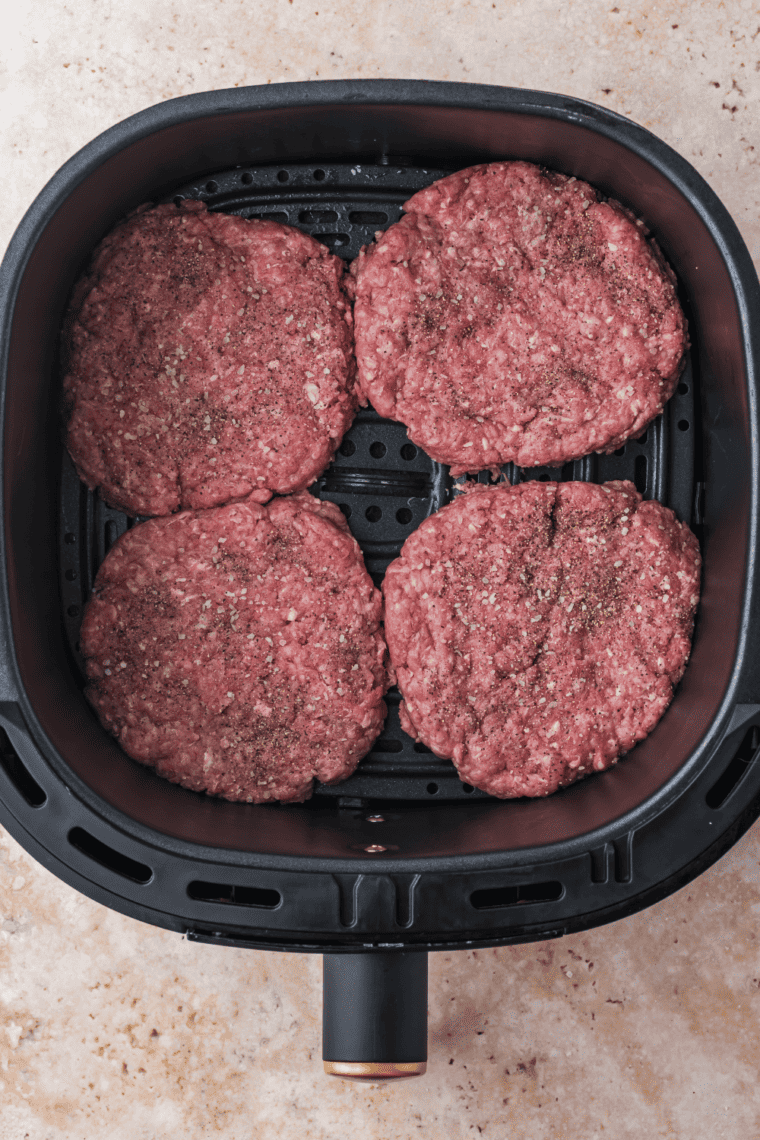 Placing patties in the air fryer basket to cook, adding cheese after cooking.