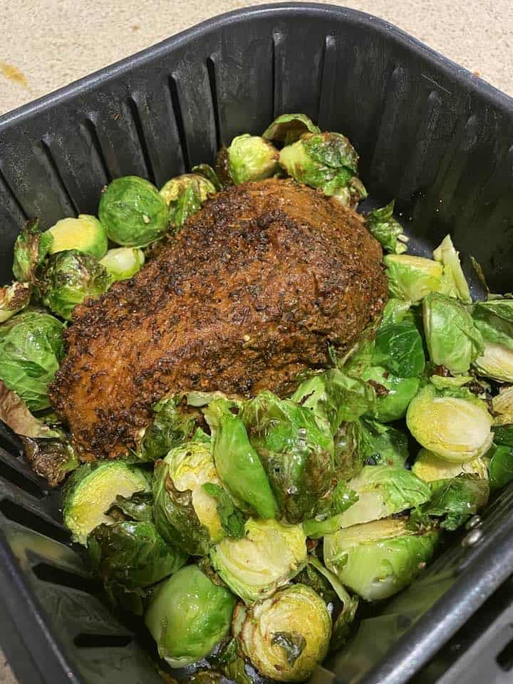 Perfectly cooked Trader Joe’s Santa Maria tri-tip roast from the air fryer, served with roasted vegetables and fresh herbs.