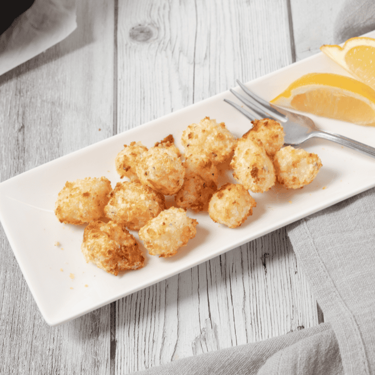 Crispy, golden Air Fryer Breaded Scallops served on a plate with a side of dipping sauce and lemon wedges.